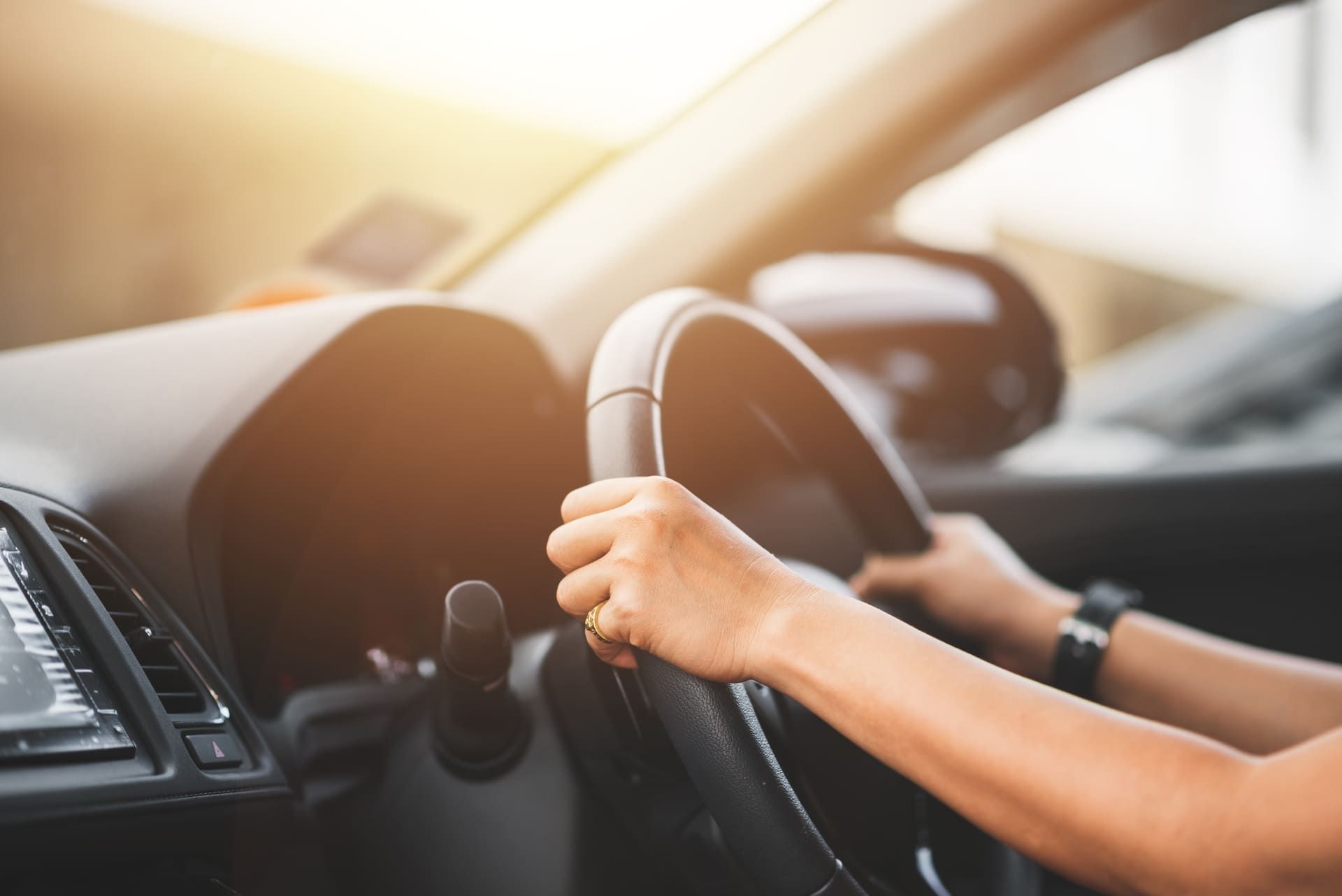 Eine Person fährt Auto und hat die Hände am Lenkrad